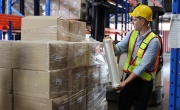 Warehouse worker with hardhat wrapping boxes in stretch film parcel on pallet