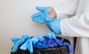 Doctor removing blue plastic gloves and throwing them in the bin