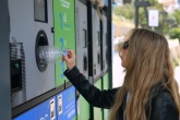 Female student putting a plastic bottle into a deposit return machine