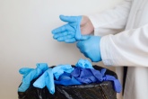 Doctor removing blue plastic gloves and throwing them in the bin