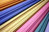 A stack of paper, with orange, blue, yellow, pink, green, and purple pieces.