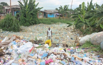 A man stands in the midst of a sea of plastic waste in Cameroon.